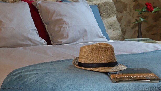 Un lit avec un chapeau de paille et un livre dessus.