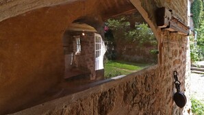 A stone archway with a view of a garden and a building outside.