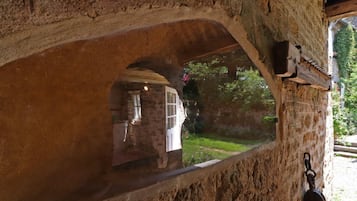 Un arco de piedra con vistas a un jardín y un edificio en el exterior.