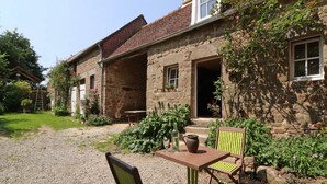 A stone building with a gravel courtyard, outdoor seating, and potted plants.