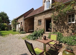 A stone building with a gravel courtyard, outdoor seating, and potted plants.
