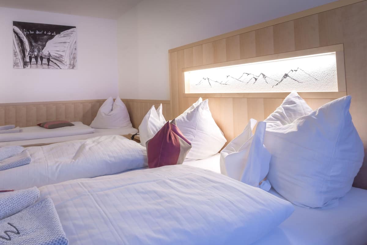 A hotel room with two beds, a wooden headboard, a wall-mounted artwork, and a window with a mountain view.