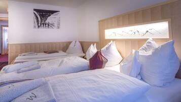 Ein Hotelzimmer mit zwei Betten, einem hölzernen Kopfteil, einem Wandbild und einem Fenster mit Blick auf die Berge.