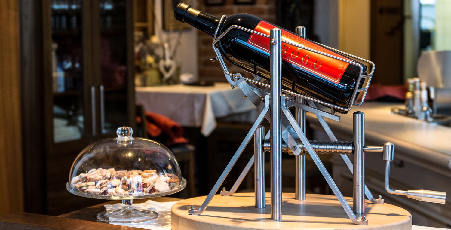 Una botella de vino sobre un soporte metálico con una campana de cristal que contiene aperitivos.