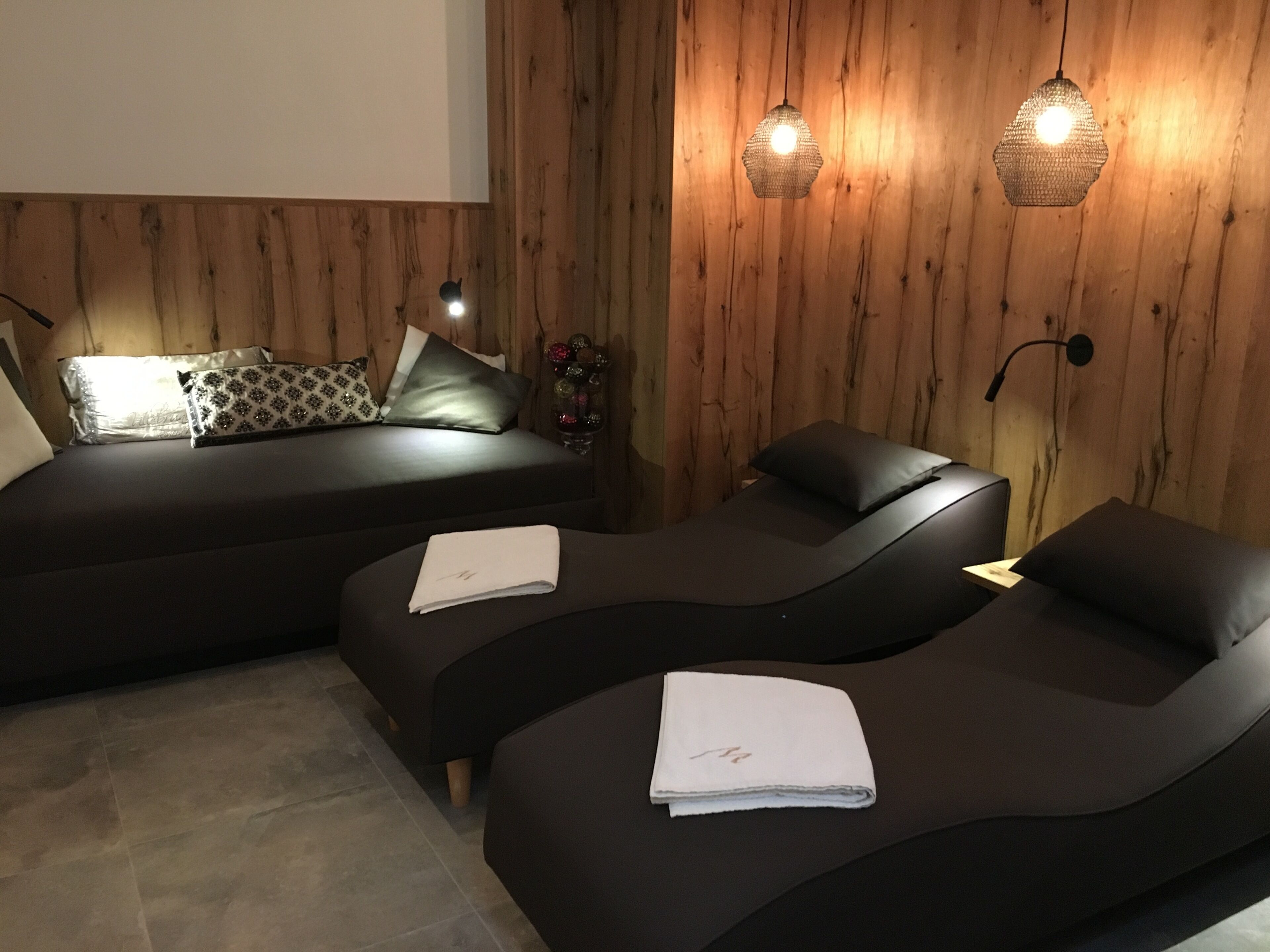 Una habitación moderna con un muro de madera, dos sofás oscuros y una mesita con una toalla.