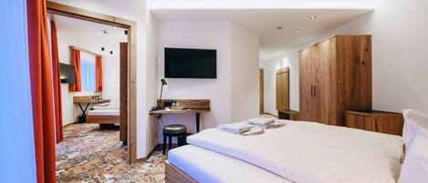Une chambre d’hôtel avec un grand lit, un bureau avec une chaise, un téléviseur fixé au mur et une armoire.