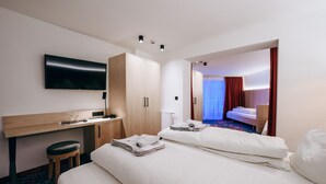 Habitación de hotel con cama, escritorio, televisor y armario.