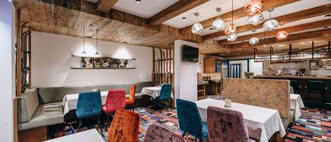 Un restaurante con vigas de madera, sillas coloridas y un piso estampado.