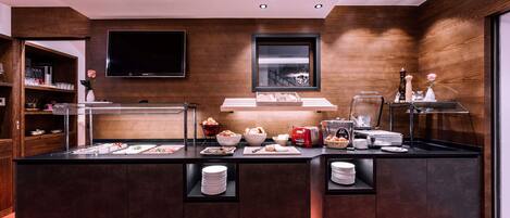 A modern kitchen with a central island, built-in shelves, and a flat-screen TV.