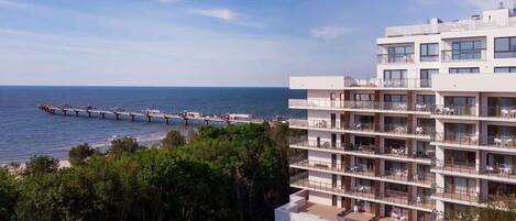 Un hôtel moderne à plusieurs étages, doté de balcons offrant une vue sur la plage et la mer.
