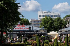 Ein Restaurant namens "Raful Restaurant & Cafe" mit Außenbestuhlung und Blick auf ein modernes Gebäude im Hintergrund.