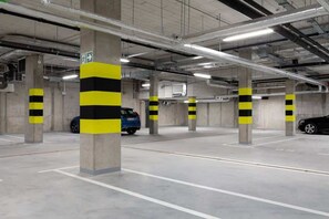 Eine überdachte Innenparkgarage mit Betonpfeilern, heller Decke und Neonbeleuchtung.