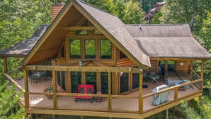 A log cabin with a large deck, outdoor seating, and a hot tub. - 🏔️ Mountain Valley Hideaway 🌳 Elevated Deck, 2 King Suites & Hot Tub (Sevierville)