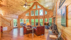 A spacious wooden cabin with a high ceiling, large windows, and a cozy seating area with a fireplace. - 🏔️ Mountain Valley Hideaway 🌳 Elevated Deck, 2 King Suites & Hot Tub (Sevierville)