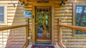 A wooden cabin entrance with a 'Welcome' sign, a tree-shaped door, and a 'Welcome to the Cabin' mat. - 🏔️ Mountain Valley Hideaway 🌳 Elevated Deck, 2 King Suites & Hot Tub (Sevierville)