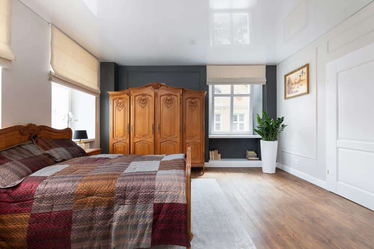 A traditional bedroom with a large wooden wardrobe, a double bed, and elegant curtains.