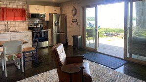 A modern kitchen with white cabinets, stainless steel appliances, and a view of a lake through large sliding glass doors.