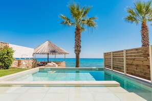 Een buitenzwembad, ligstoelen bij het zwembad