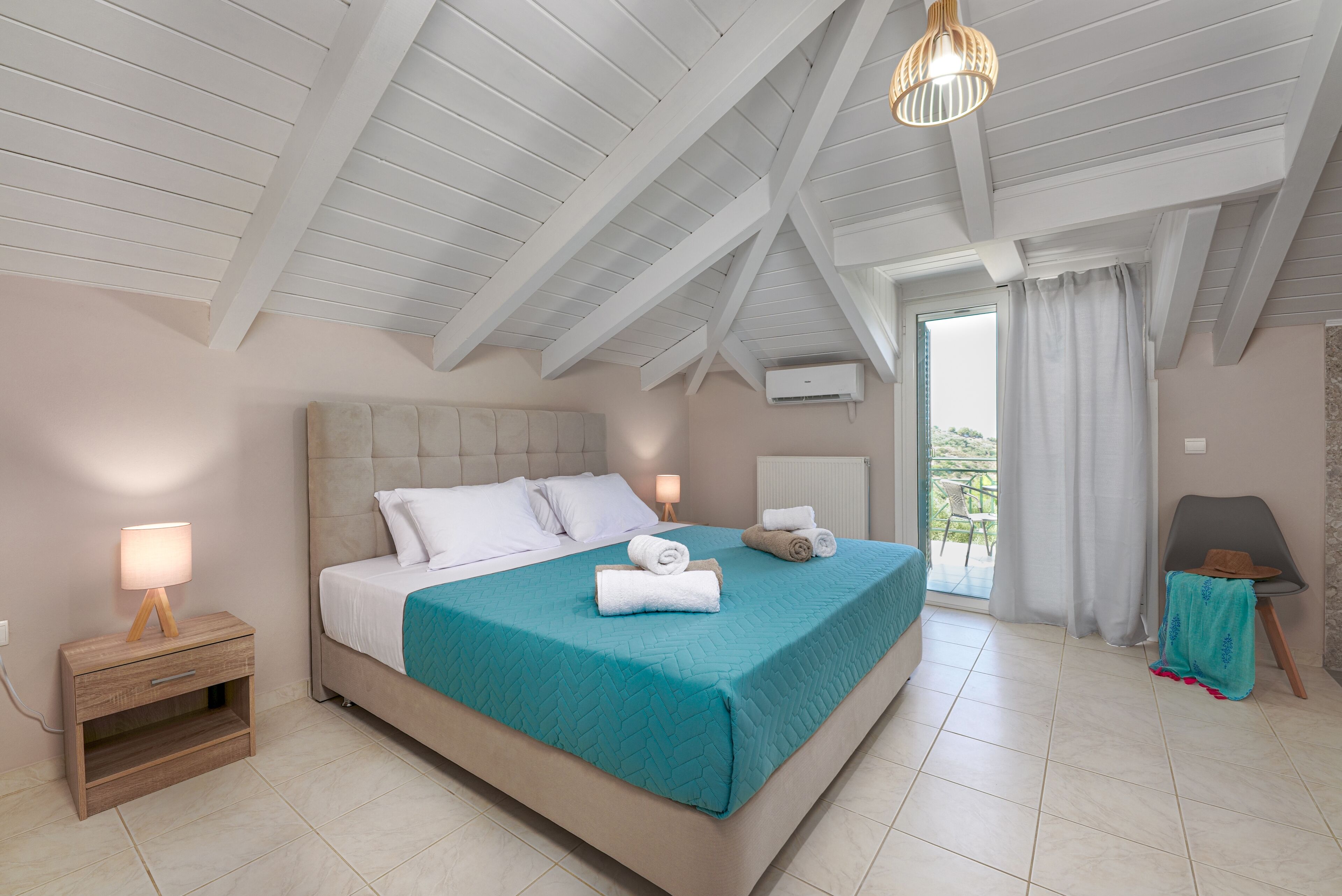Un dormitorio con una cama grande, una mesita de noche, una lámpara y vistas al exterior.