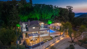 A modern villa with a swimming pool, a covered patio, and a stone retaining wall. - Andromeda Luxury Villa (Zakynthos)