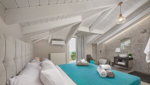 A modern bedroom with a large bed, a bathroom with a stone wall, and a view of the outdoors. - Andromeda Luxury Villa (Zakynthos)