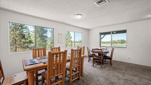 A dining area with wooden furniture, large windows, and a carpeted floor. - Amazing Views! 3,000 sq ft cabin!  Hot Tub, & Game Room! (Big Bear City)