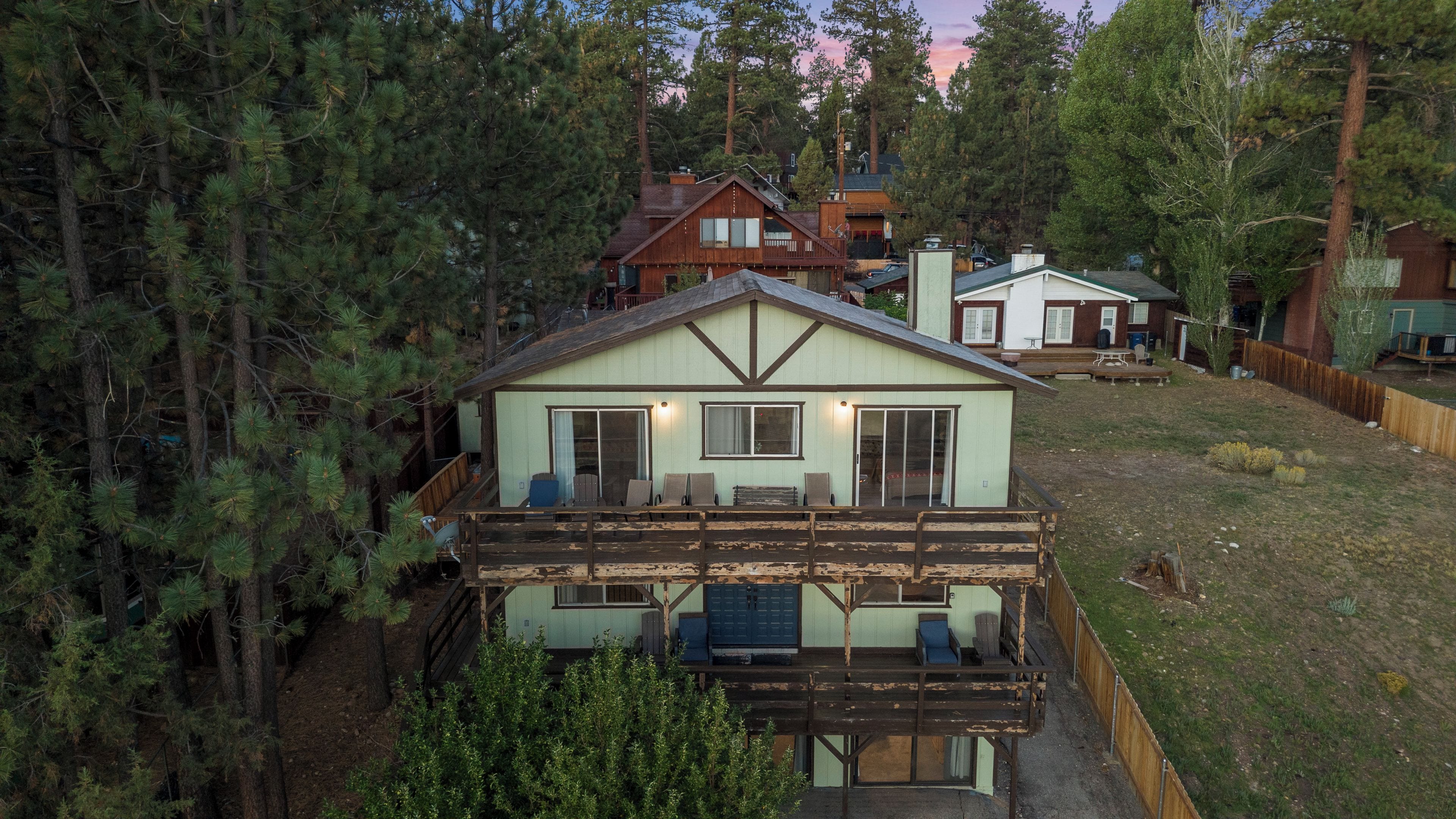 A cabin with a deck, surrounded by trees.