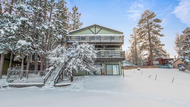 A multi-story building with a green roof and a covered outdoor area, surrounded by snow-covered trees. - Amazing Views! 3,000 sq ft cabin!  Hot Tub, & Game Room! (Big Bear City)
