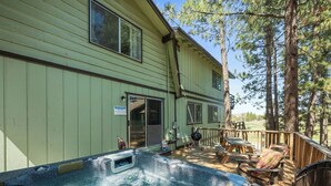 A spa area with a hot tub, deck chairs, and a wooden deck. - Amazing Views! 3,000 sq ft cabin!  Hot Tub, & Game Room! (Big Bear City)