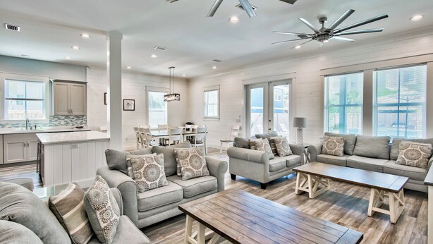 A spacious living area with a large sofa set, a wooden coffee table, and a ceiling fan.