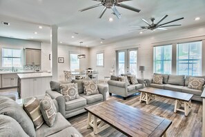 A spacious living area with a large sofa set, a wooden coffee table, and a ceiling fan. - Utopia Estate with Saltwater Pool & Golf Cart (Miramar Beach)