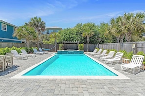 A rectangular swimming pool with a tiled deck, surrounded by white lounge chairs and a wooden fence. - Utopia Estate with Saltwater Pool & Golf Cart (Miramar Beach)