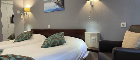 Habitación de hotel con una cama grande, dos lámparas de noche, un cuadro en la pared y una silla.