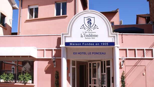 A pink building with a sign reading "L'Embleme Boutique Hotel" and "Maison Fondee en 1905 EX HOTEL LE PONCEAUX". - L'Embleme Boutique Hotel (Beaurepaire)