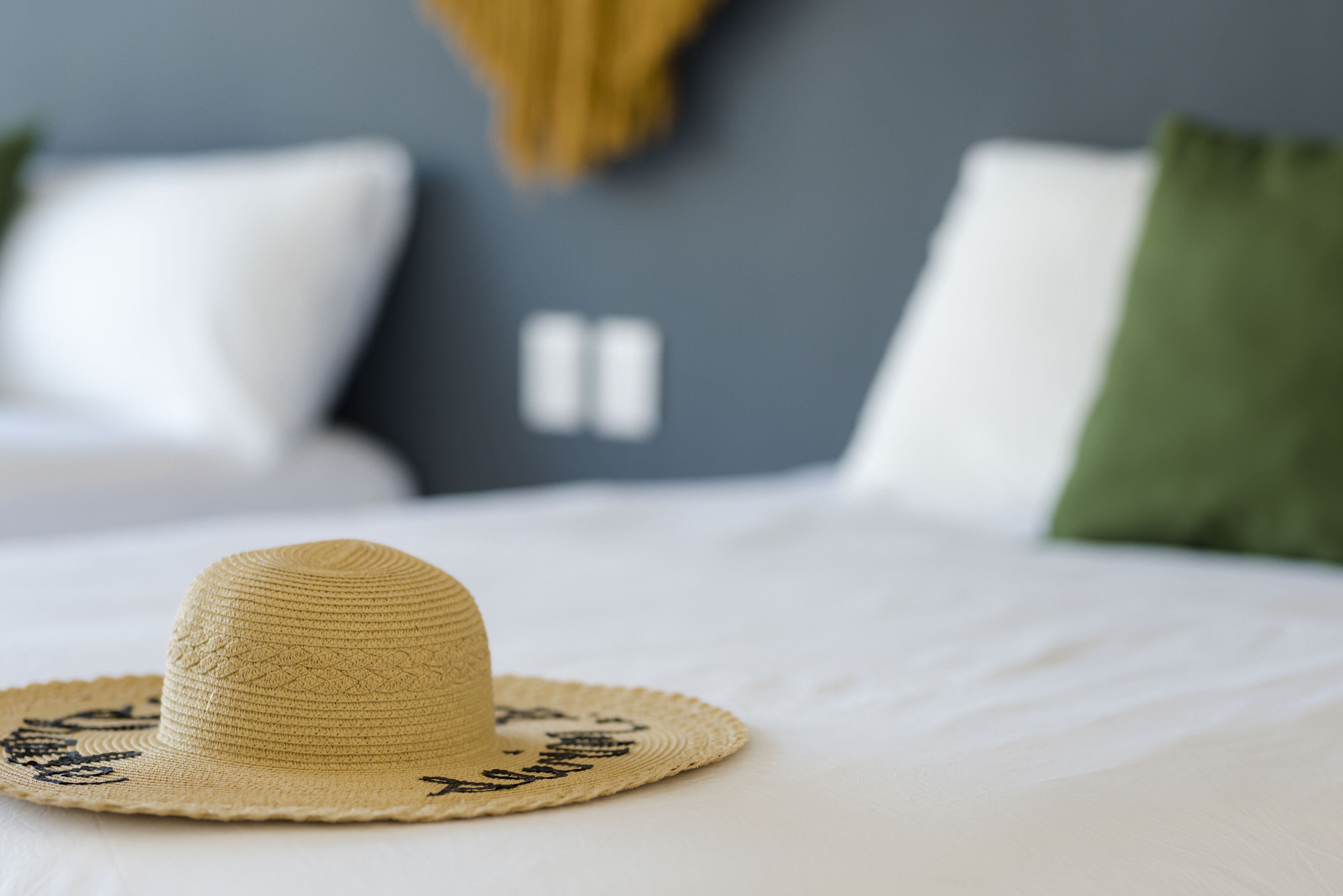 Un sombrero de paja con texto sobre una cama en una habitación de hotel.