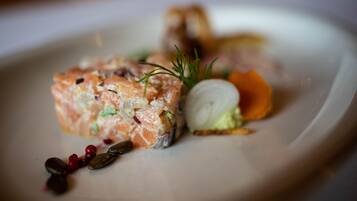 A dish with salmon, vegetables, and garnishes on a plate.