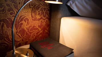 A bedside table with a lamp, a book titled "James Joyce Ulysses," and a patterned wall.