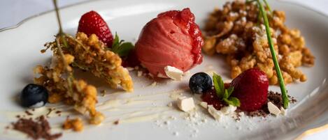 Un plato de postre con diversas frutas y una bola de helado.