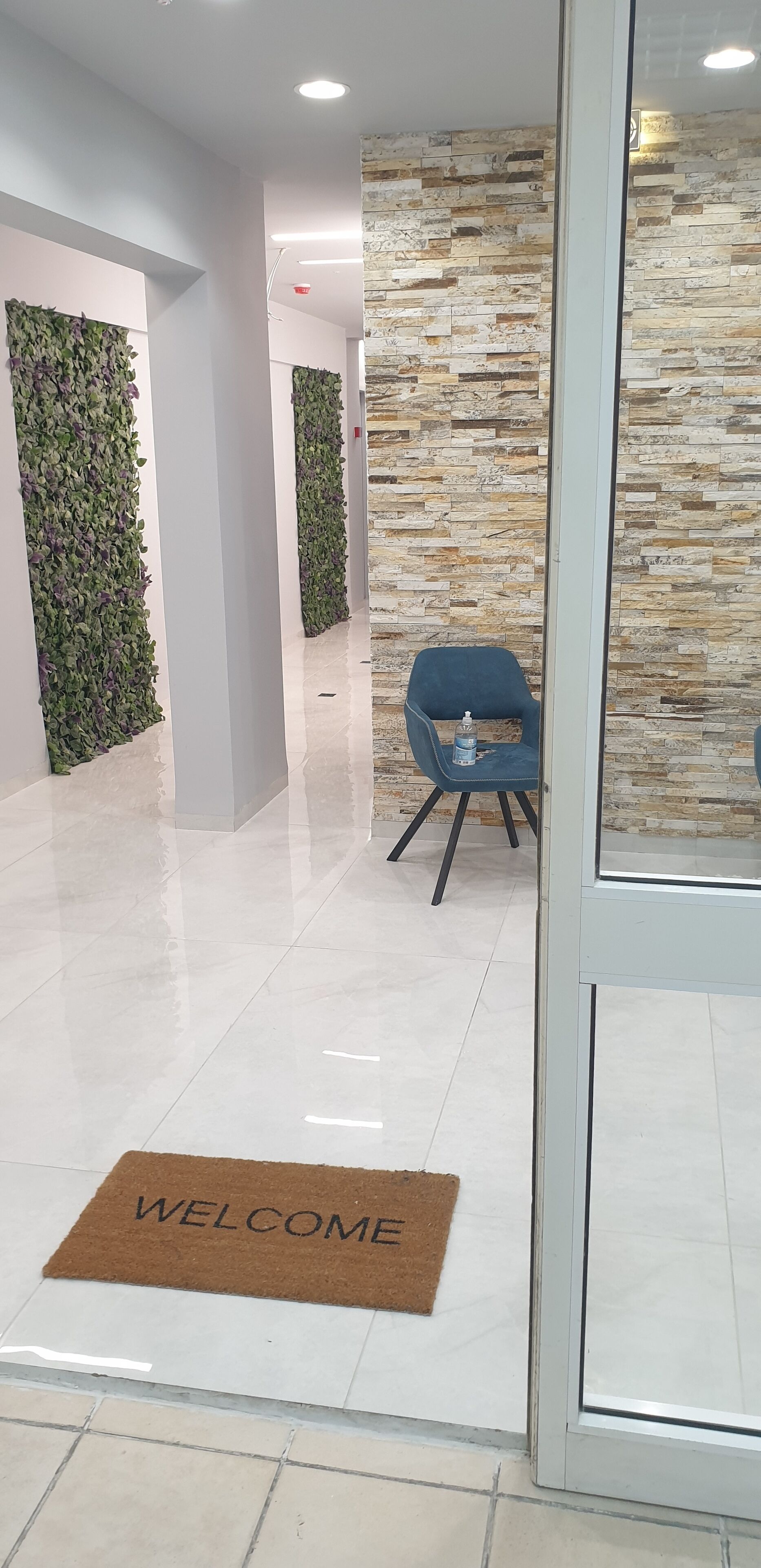 Un vestíbulo moderno con pared de piedra, una silla azul y un felpudo.