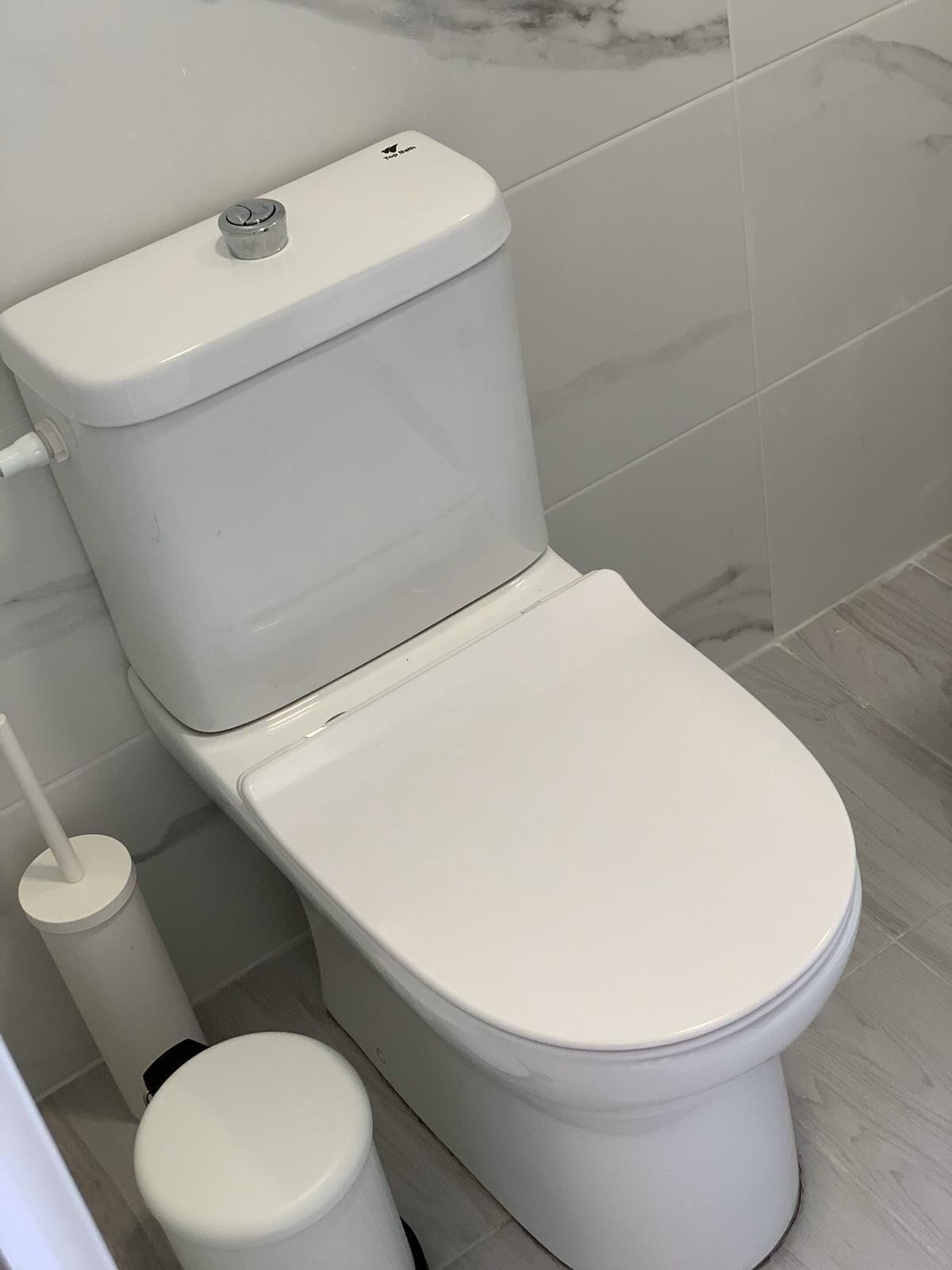 Des toilettes blanches, dotées d’une poignée de chasse d’eau et d’un accessoire de type bidet.