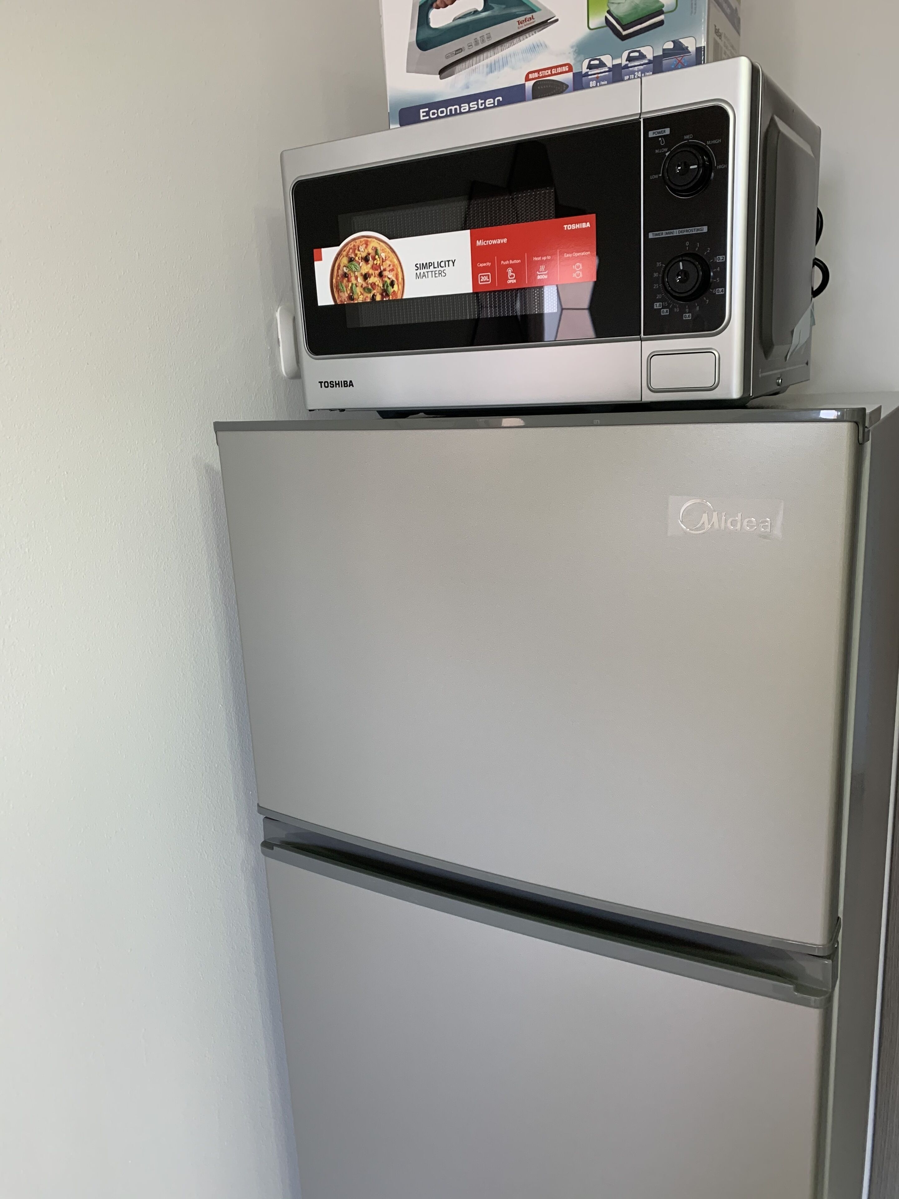 A refrigerator with a microwave on top.