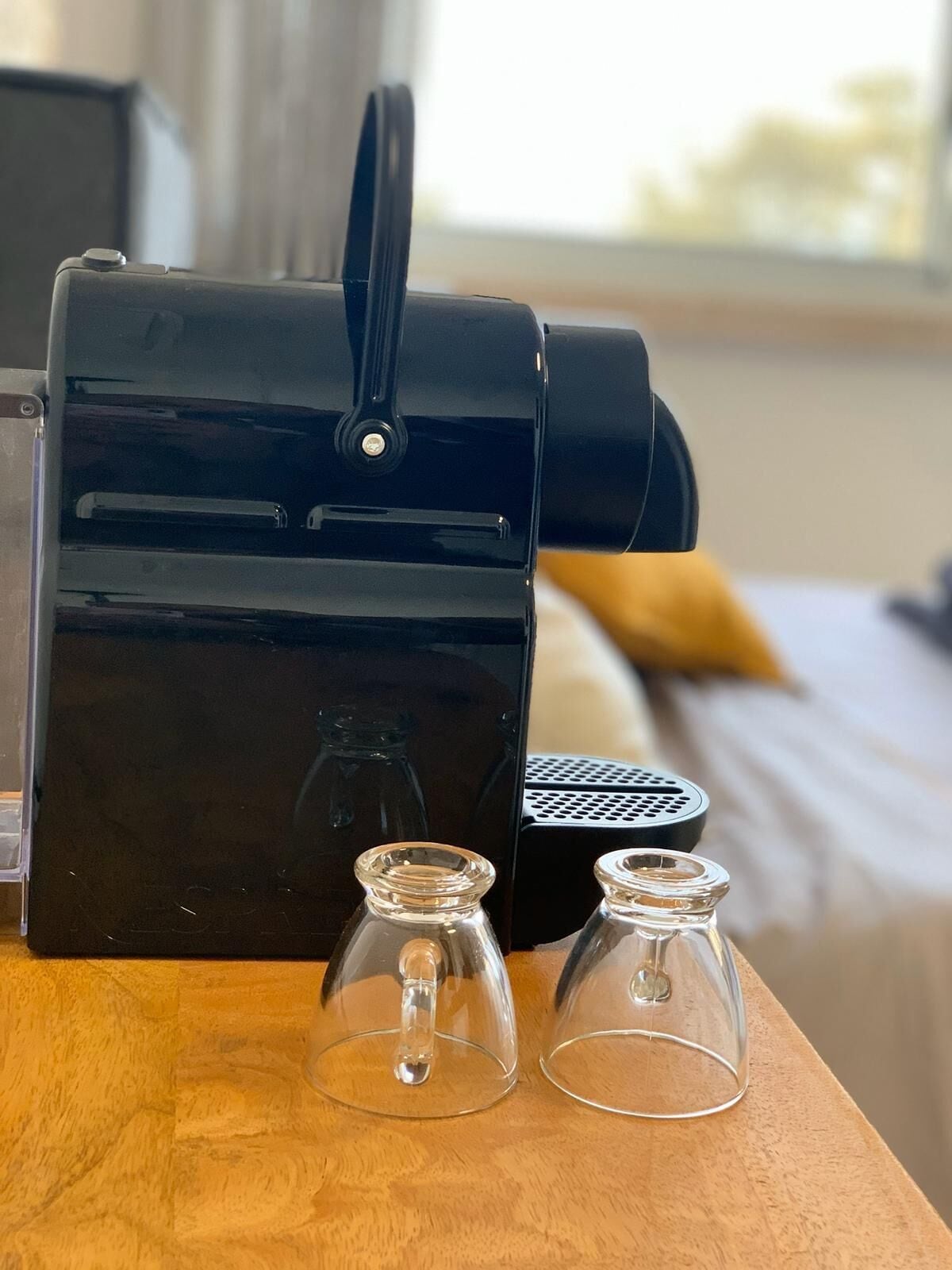 Una cafetera negra sobre una mesa de madera con dos botellas de vidrio transparente.