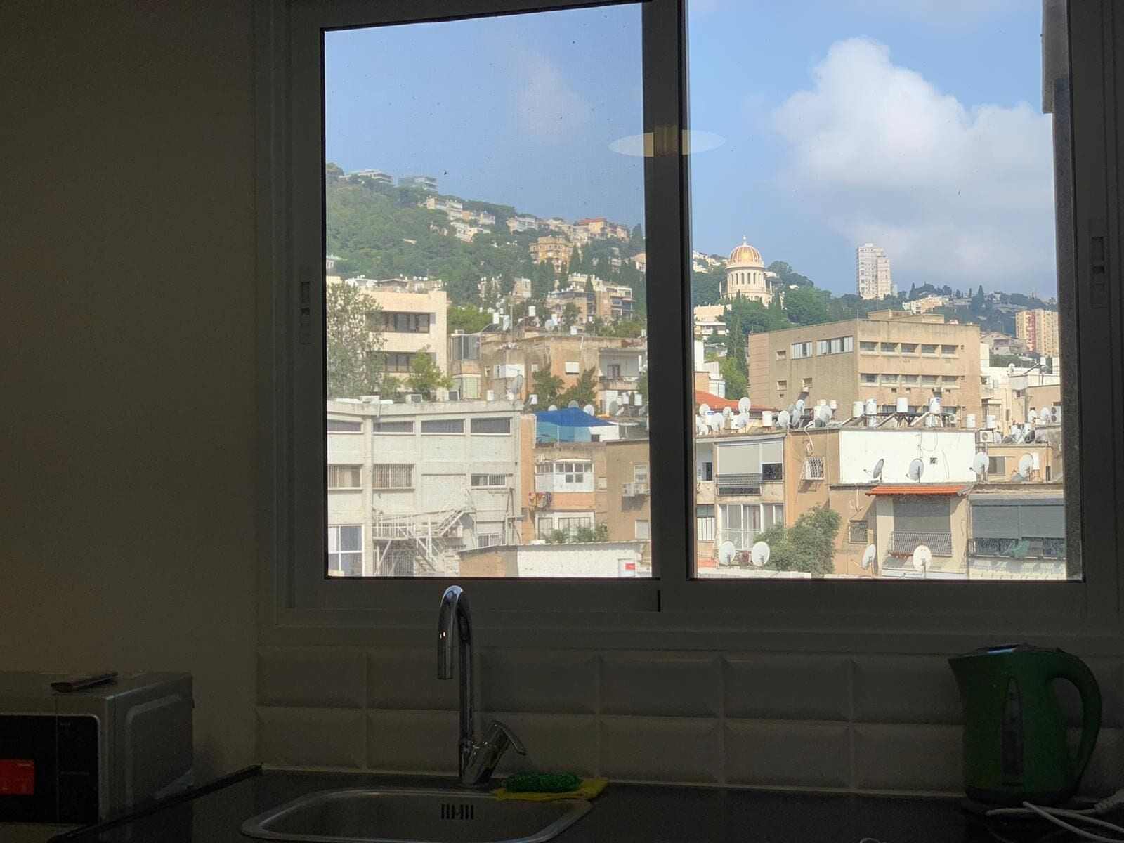 Una cocina con vista a la ciudad, incluyendo una colina con edificios y una estructura cúpula destacada.