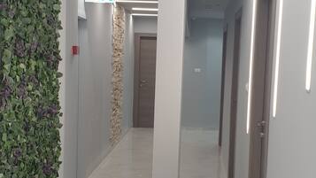Un pasillo moderno con una pared verde, un muro decorativo de piedra y un cartel que indica una salida.
