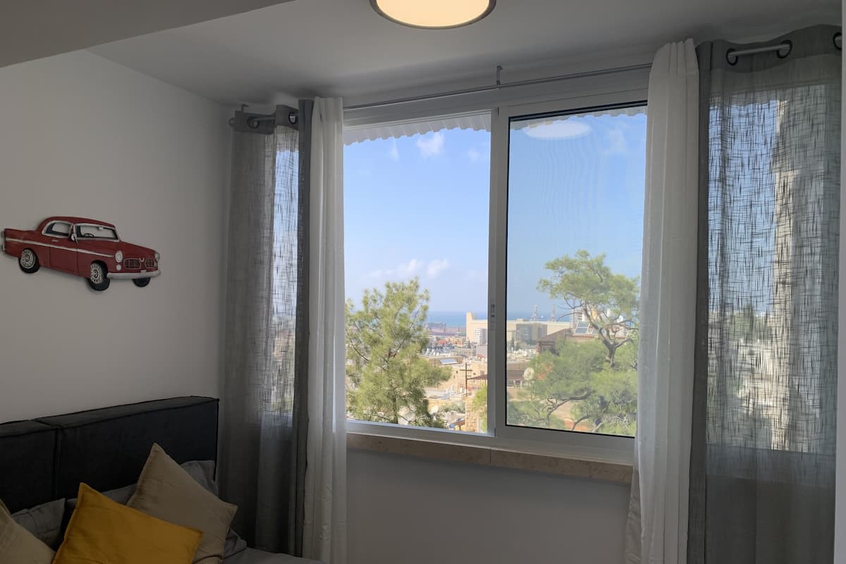 A bedroom with a bed, a window with curtains, and a wall-mounted car decoration.