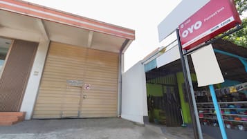 Um edifício com uma porta de obturador fechada, uma placa anunciando OYO Forrest'in e uma vitrine com diversos itens.
