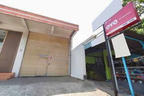 A building with a closed shutter door, a signboard advertising OYO Forrest'in, and a storefront with various items. - OYO 3309 Forrestinn (Kediri)