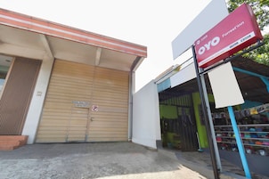 Un edificio con una puerta cerrada por una persiana, un letrero que anuncia OYO Forrest'in y un escaparate con diversos artículos.