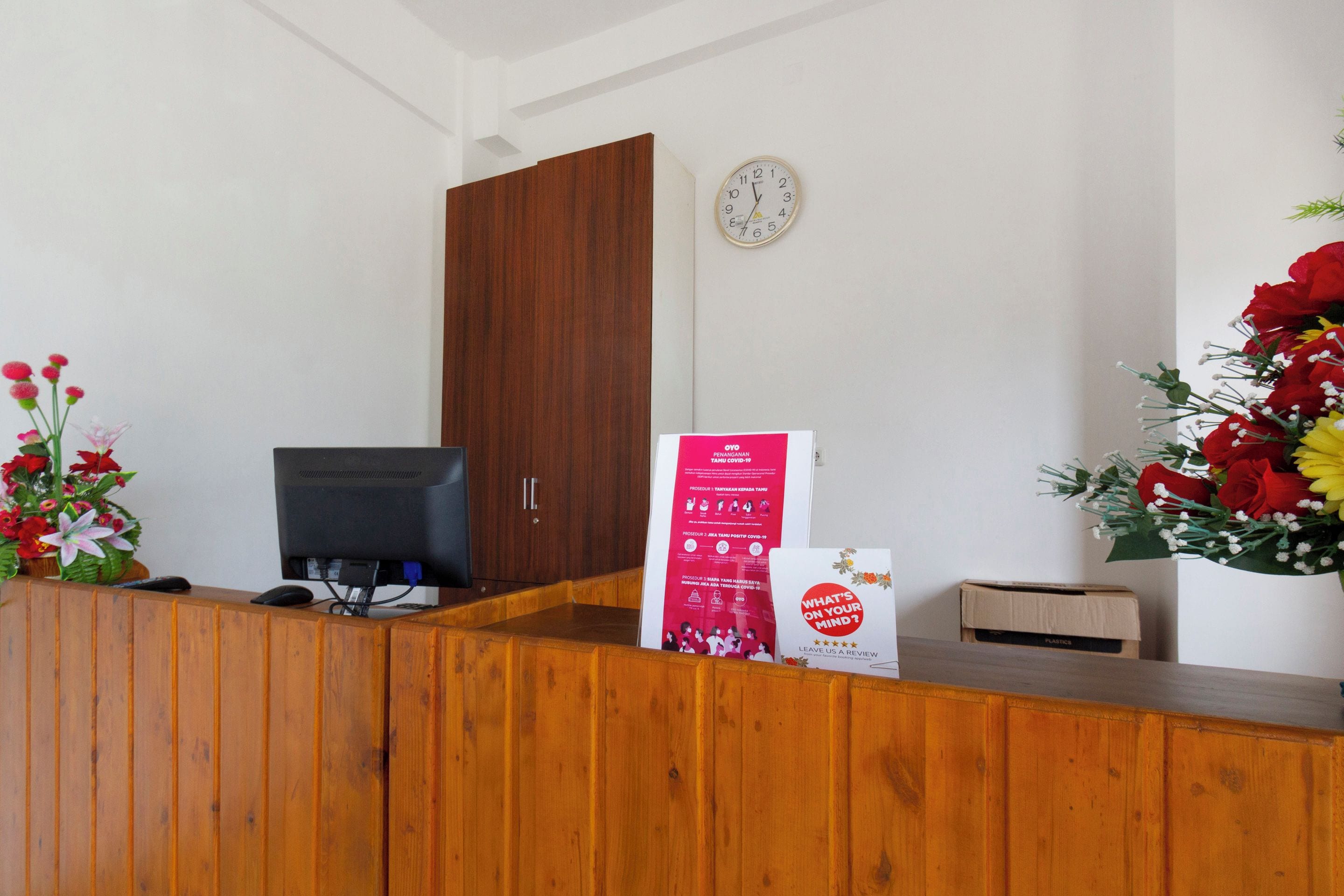A reception desk with a computer, a clock, and a poster.
