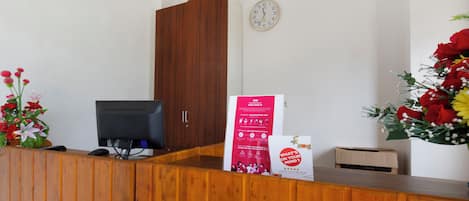 A reception desk with a computer, a clock, and a poster.